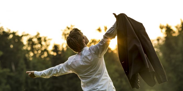 Young businessman holding his jacket with arms spread widely